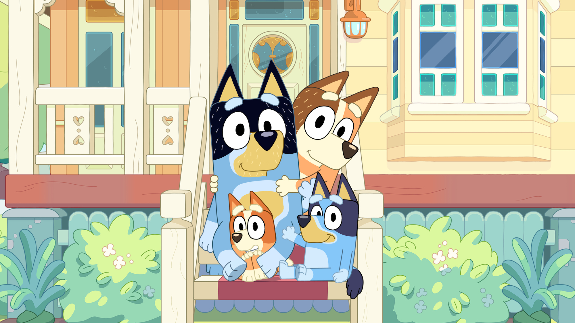 Die Familie von Bluey, einer australischen Zeichentrickserie, sitzt auf der Treppe vor der Haustür und winken in die Kamera
